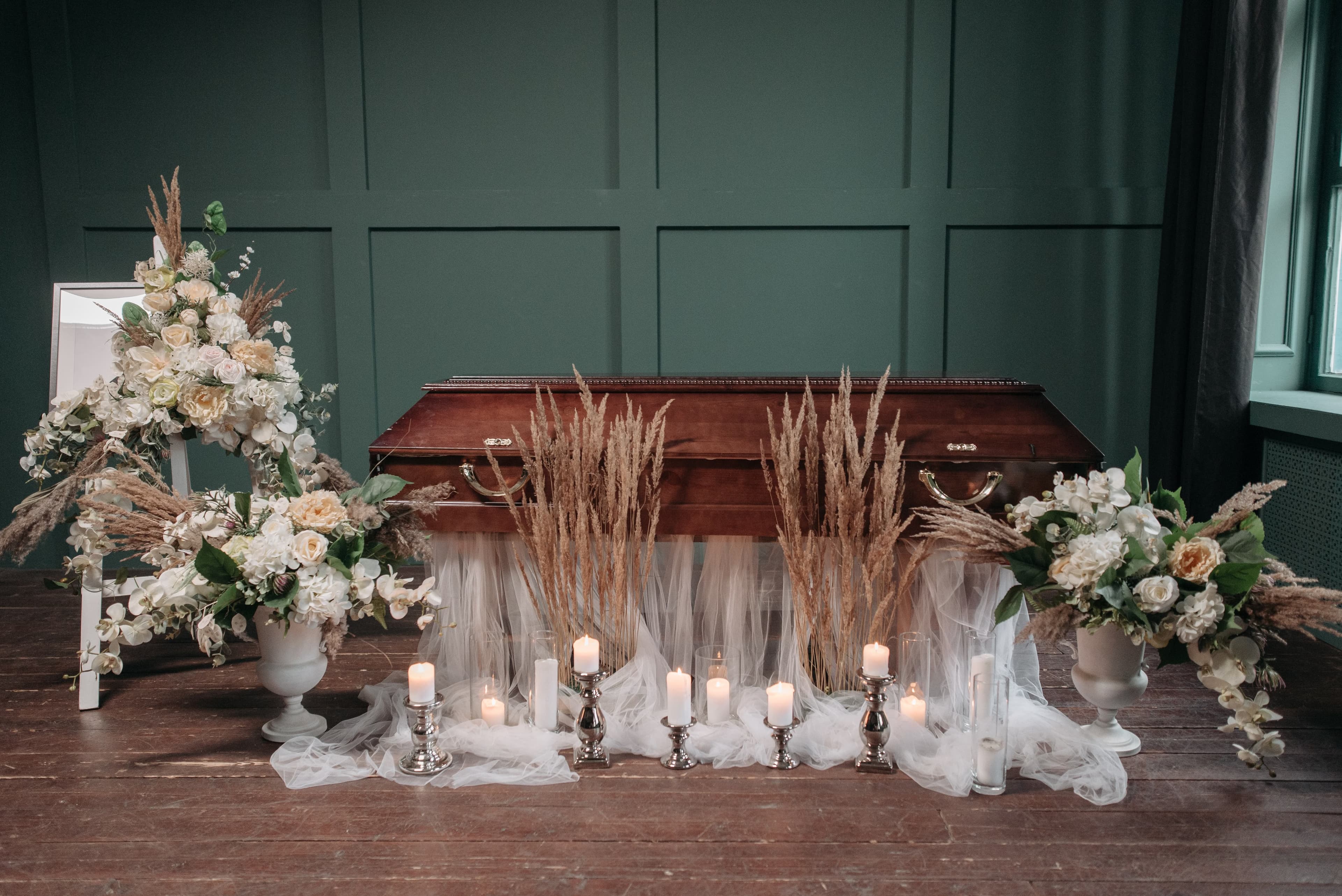 A casket surrounded by white sympathy flowers and candles