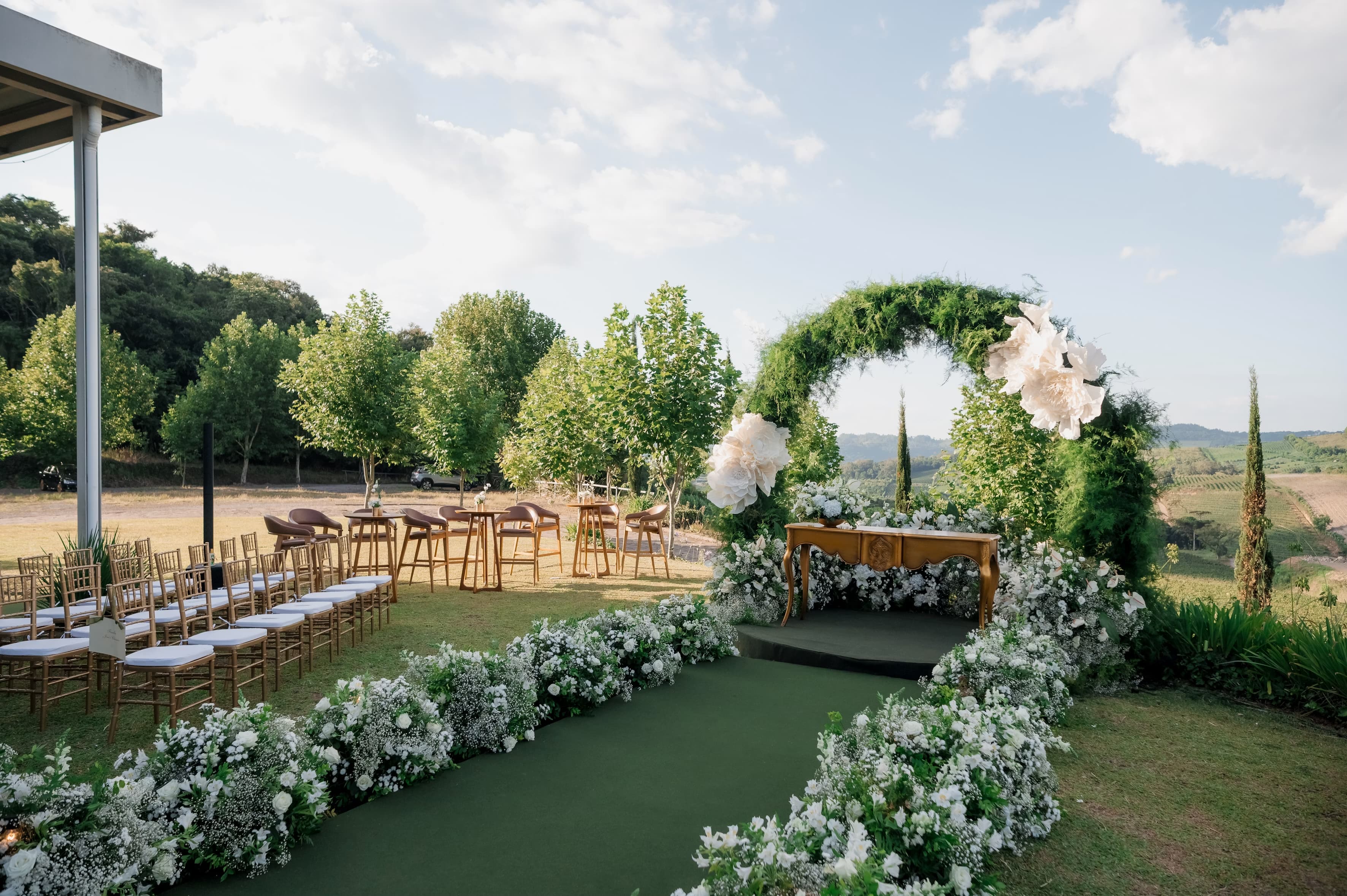 An outdoor wedding ceremony with a floral arch